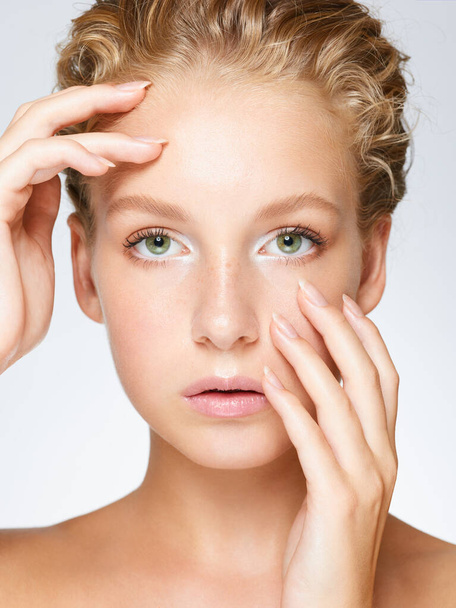 Портрет молодой блондинки с зелеными глазами и чистой кожей на белом фоне - Фото, изображение