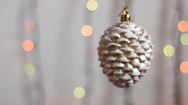 Giocattolo di albero di Natale nella forma di un cono di abete. Primo piano. Il bel giocattolo di albero di Natale pende sullo sfondo delle luci di anno nuovo multicolore. Giocattolo di albero di Natale nella forma di un cono di abete. - Filmati, video