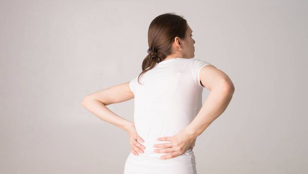 Attractive teenage girl suffers from backache. All on white background - Photo, Image