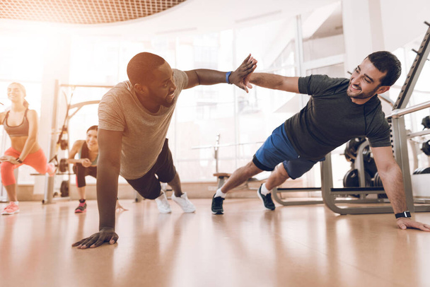 Two men squeeze off the floor in a modern gym. - 写真・画像