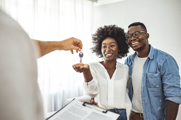 Couple Getting Keys From Realtor Of Their New Home. Portrait of financial adviser congratulating to a young couple for buying a new house. African-American  family buy new house - Foto, afbeelding