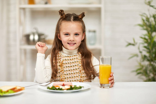 little child girl having breakfast - fried egg and orange juice - Foto, Bild