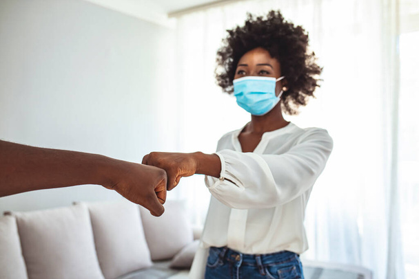 Male and female colleagues fist bumping, group of young business people with protective face masks. New normal greeting with fist bump. Two people wearing protective face mask and greeting with fist bump - Foto, afbeelding