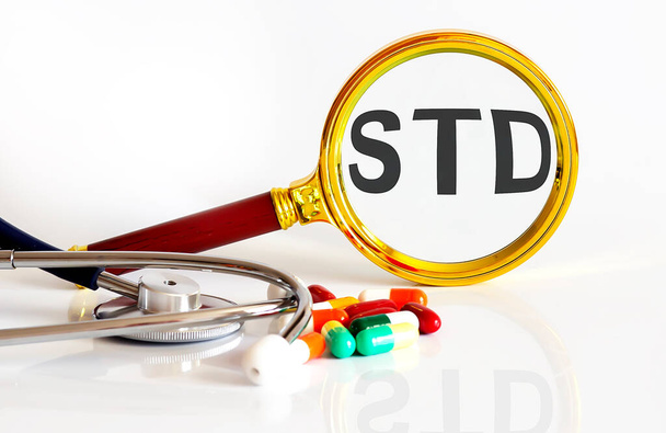 Lente de aumento con texto STD con herramientas médicas, pastillas - Foto, imagen