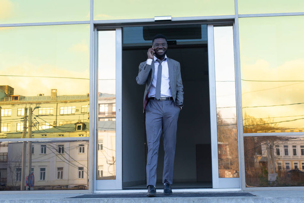 de Afro-Amerikaanse man loopt gelukkig het gebouw uit - Foto, afbeelding