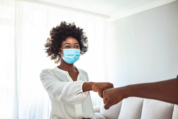 Young women wearing a hygienic face mask greeting by bumping fists together. Teenage realizing the self-protection against coronavirus (Covid-19) infection. - Foto, Bild