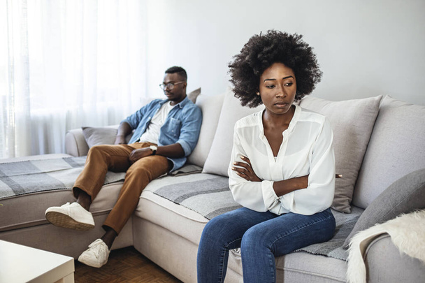 Shot of a young couple having relationship problems at home. Upset couple at home. Handsome man and beautiful young woman are having quarrel. Sitting on sofa together. Family problems. - Фото, изображение