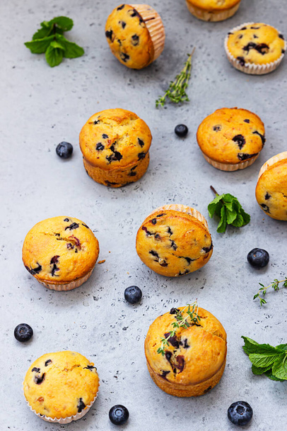 Fresh homemade delicious blueberry muffins decorated with thyme, fresh berries and mint on grey concrete background. Top view. - Fotografie, Obrázek