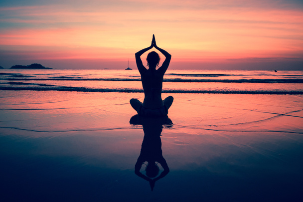 Yoga femme assise sur la côte de la mer au coucher du soleil
. - Photo, image