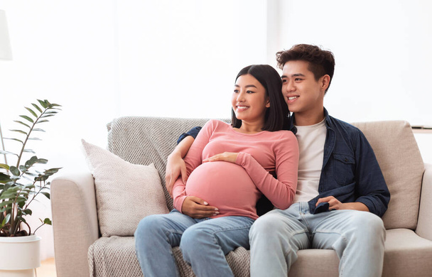 Aasialainen pari katsomassa televisiota odottaa vauva istuu kotona - Valokuva, kuva
