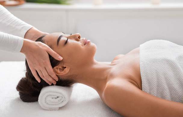 Entspannte asiatische Dame bekommt Kopfmassage im Wellness-Salon und genießt Schönheitsbehandlung - Foto, Bild
