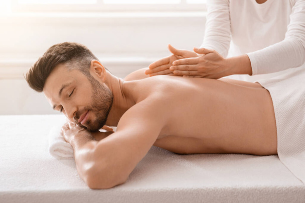 Богатый мужчина средних лет наслаждается лечебным массажем в спа - Фото, изображение