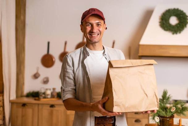 Young delivery man holding and carrying a cardbox. Buy food online in quarantine concept. - Foto, Imagem