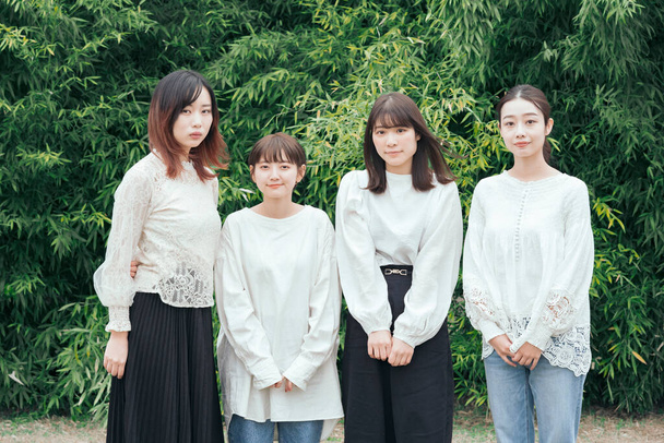 Vier Japanse vrouwen kijken naar de camera zij aan zij buiten - Foto, afbeelding