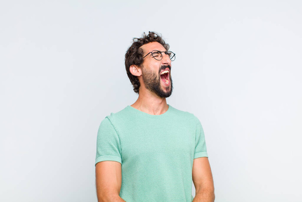 young bearded man screaming furiously, shouting aggressively, looking stressed and angry - 写真・画像