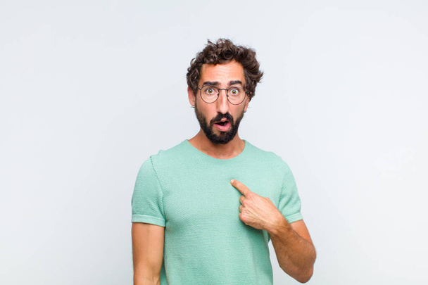 young bearded man looking shocked and surprised with mouth wide open, pointing to self - Foto, immagini