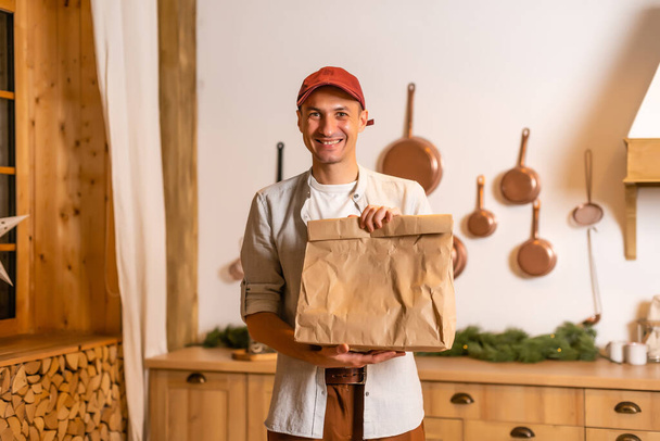 Young delivery man holding and carrying a cardbox. Buy food online in quarantine concept. - Φωτογραφία, εικόνα
