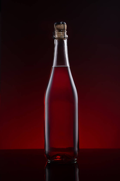 Butelka wina Lambrusco na czerwonym ciemnym tle. - Zdjęcie, obraz