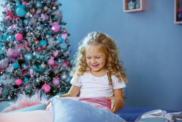 Девочка рядом с елкой играет с подушками счастливой - Фото, изображение