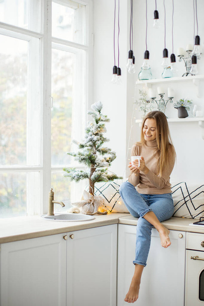Young attractive woman at home near the Christmas tree. - Foto, Imagen
