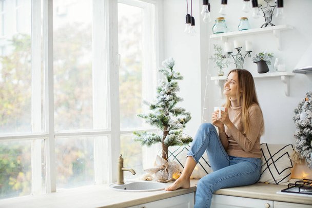 Young attractive woman at home near the Christmas tree. - Foto, Imagen
