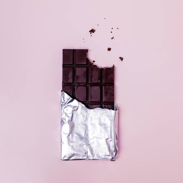 Bited bar of chocolate in foil with crumbs - Фото, зображення