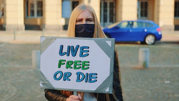 Γυναίκα με μάσκα και πανό διαμαρτυρίας που καλεί να ζήσει ελεύθερη ή να πεθάνει. - Φωτογραφία, εικόνα