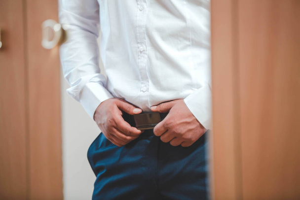 A selective focus shot of a man holding to his belt buckle - Fotoğraf, Görsel