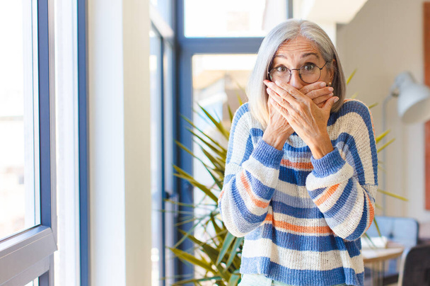 middle age woman covering mouth with hands with a shocked, surprised expression, keeping a secret or saying oops - Foto, Bild