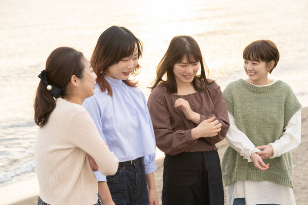 Quattro asiatiche giovani donne parlando felicemente nel crepuscolo - Foto, immagini