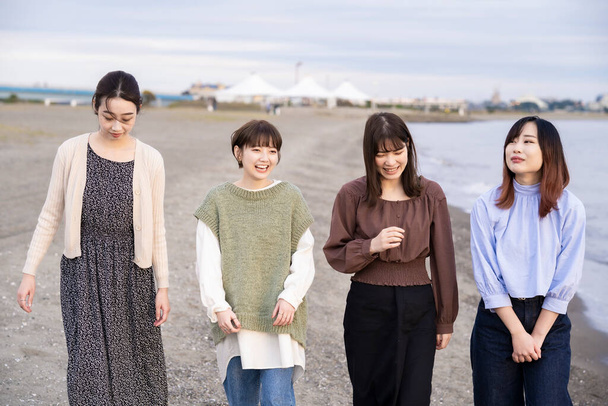 Cuatro asiático jóvenes mujeres hablando felizmente en el atardecer - Foto, imagen