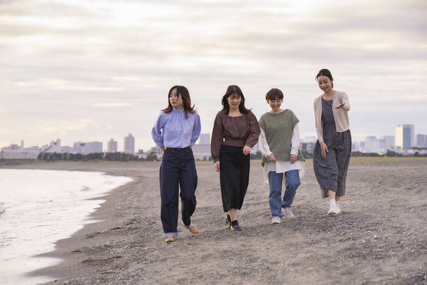 Cuatro mujeres jóvenes caminando por el mar al atardecer - Foto, imagen