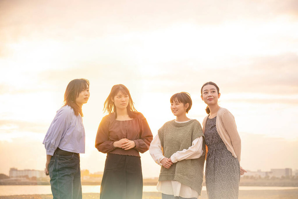 Vier asiatische junge Frauen unterhalten sich fröhlich in der Dämmerung - Foto, Bild