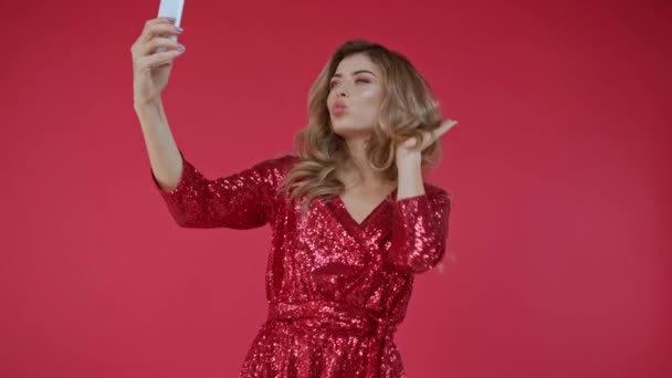 Χαρούμενη γυναίκα με φόρεμα λαμβάνοντας selfie στο smartphone που απομονώνονται σε κόκκινο  - Πλάνα, βίντεο