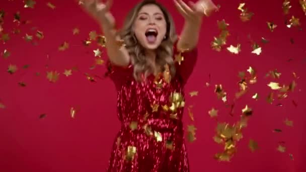 Movimento lento da mulher no vestido perto de cair confete no fundo vermelho  - Filmagem, Vídeo