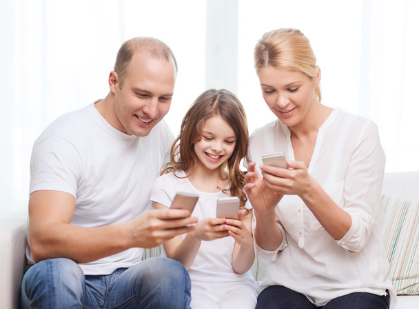 Parents and little girl with smartphones at home - 写真・画像