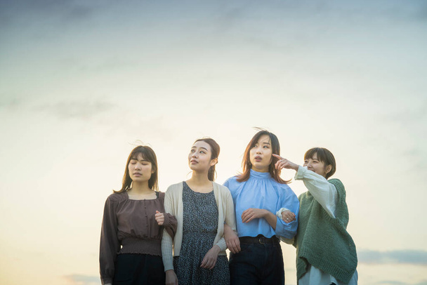 4 jóvenes mujeres asiáticas mirando el paisaje distante en la noche - Foto, Imagen