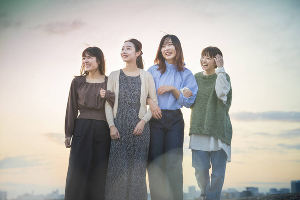 4 junge asiatische Frauen blicken abends auf die ferne Landschaft - Foto, Bild