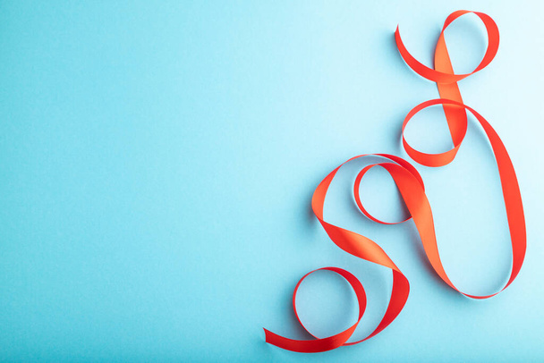 Red coral ribbon on a blue pastel background. Celebration concept. Top view, copy space, flat lay. - Fotoğraf, Görsel