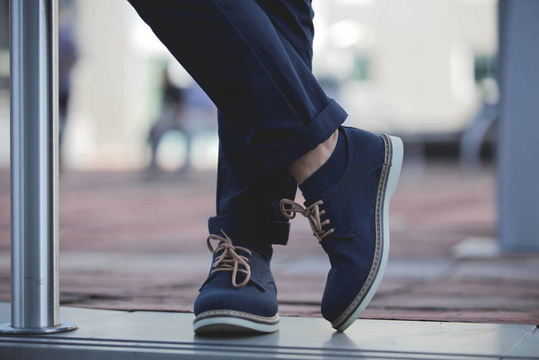 A closeup of a male wearing blue chukka boots and standing with crossed legs outdoors - Foto, Bild