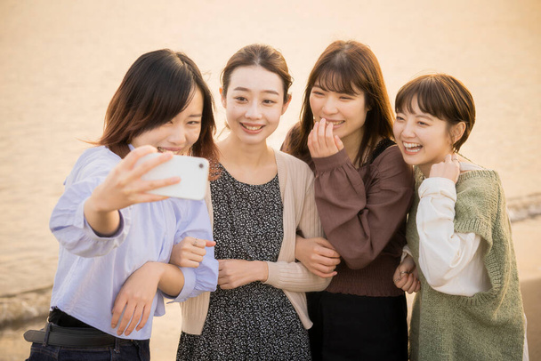 4 mujeres jóvenes tomando una foto conmemorativa con un smartphone - Foto, Imagen