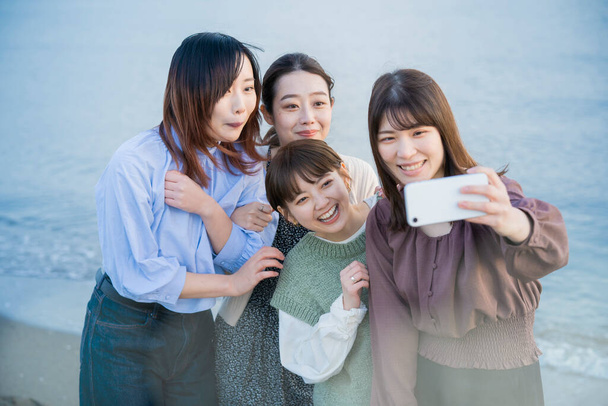 4 jonge vrouwen maken een herdenkingsfoto met een smartphone - Foto, afbeelding