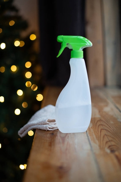 Una botella de detergente y trapo en el fondo de las luces de Año Nuevo. Limpieza profesional general antes de Navidad. Pulverizar la desinfección antes de la fiesta - Foto, Imagen