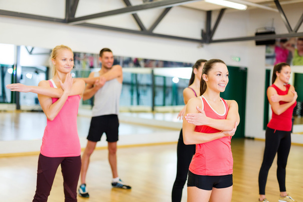 Group of smiling people stretching in the gym - 写真・画像