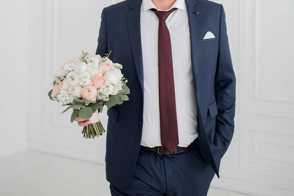 the groom at the wedding holds bouquet of roses - Φωτογραφία, εικόνα