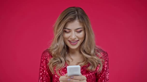 Femme souriante utilisant un smartphone isolé sur rouge  - Séquence, vidéo