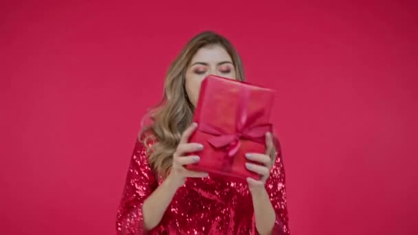 Mujer positiva sosteniendo presente aislada sobre rojo  - Metraje, vídeo