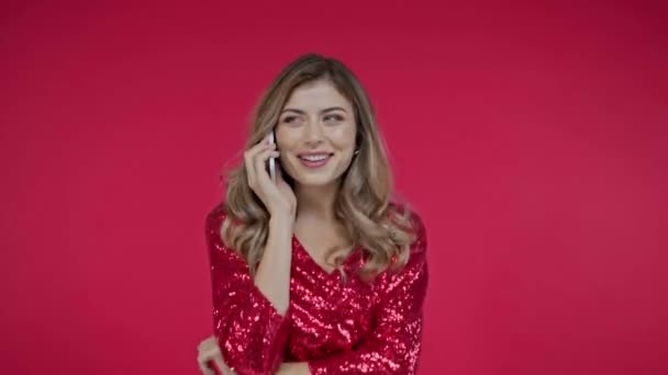 Mulher sorridente no vestido falando no smartphone isolado no vermelho  - Filmagem, Vídeo