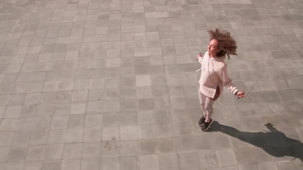 Imágenes de primera vista de la mujer caucásica en forma saltando con la cuerda quemando calorías en el entrenamiento al aire libre de la mañana - Metraje, vídeo