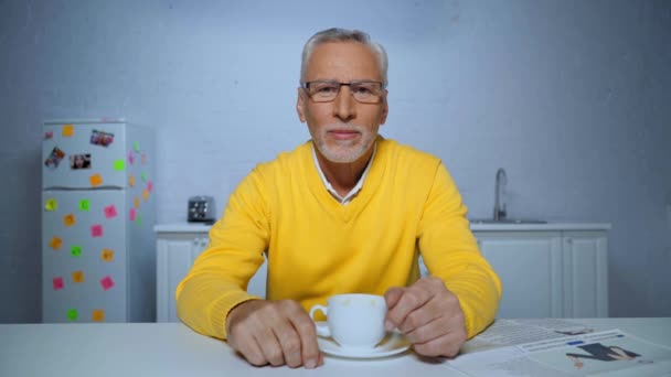 positivo uomo di mezza età bere caffè e parlare durante la chiamata skype a casa - Filmati, video